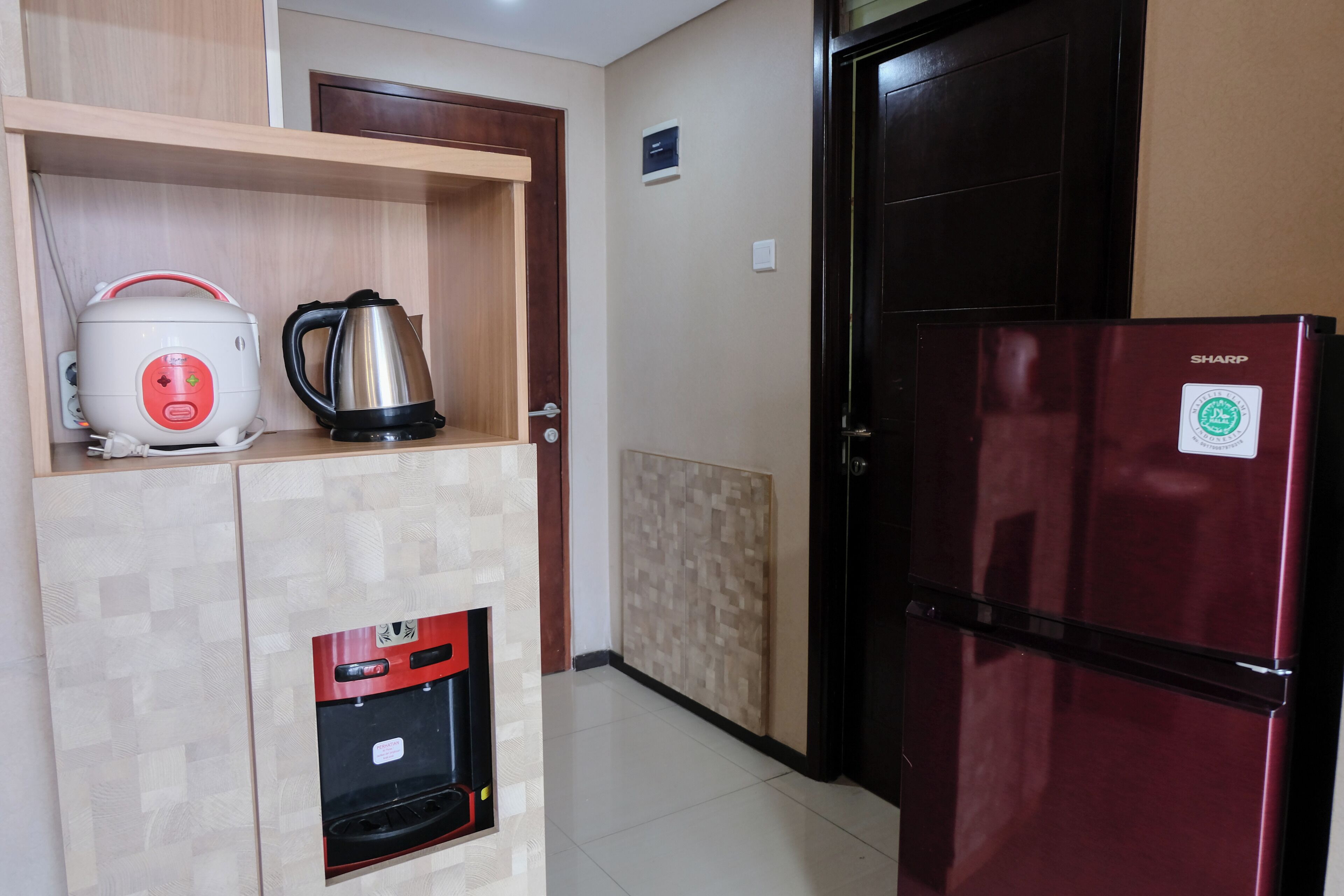 Una cocina compacta con cafetera integrada, hervidor y refrigerador.