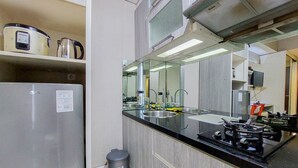 Une cuisine moderne dotée d’appareils électroménagers en acier inoxydable, d’un évier encastré et d’un grand miroir au-dessus du plan de travail.