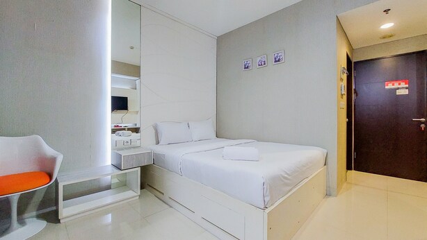 Une chambre d’hôtel moderne équipée d’un lit, d’un coin salon, d’un miroir et d’une porte.
