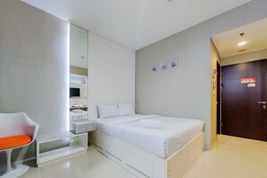 Une chambre d’hôtel moderne équipée d’un lit, d’un coin salon, d’un miroir et d’une porte.