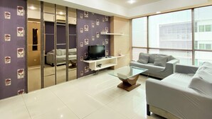A modern living room with a glass coffee table, a sofa, a TV, and a sliding wardrobe. - Modern Look And Comfort 2Br Kemang Village Apartment (Jakarta)