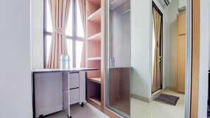 Une pièce comprenant un bureau, une armoire, une porte-fenêtre coulissante et une fenêtre avec des rideaux.