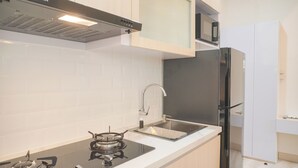 Une cuisine moderne avec des meubles blancs, une cuisinière noire, un évier en acier inoxydable et un réfrigérateur noir.