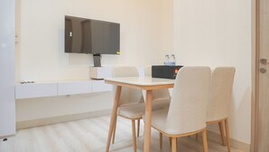 Un espace repas moderne comprenant une table, des chaises, un téléviseur à écran plat fixé au mur et un mini-bar.
