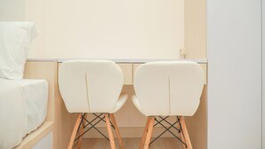 Une pièce comprenant un lit, deux chaises blanches et un bureau en bois.