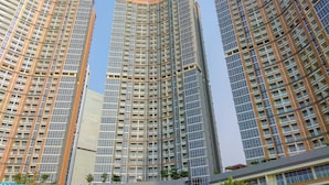 Three high-rise buildings with a modern architectural design, featuring a grid-like facade with numerous windows. - Comfortable 1Br At Gold Coast Apartment (Jakarta)