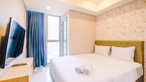 A hotel room with a bed, a TV on a desk, and a window with curtains. - Comfortable 1Br At Gold Coast Apartment (Jakarta)