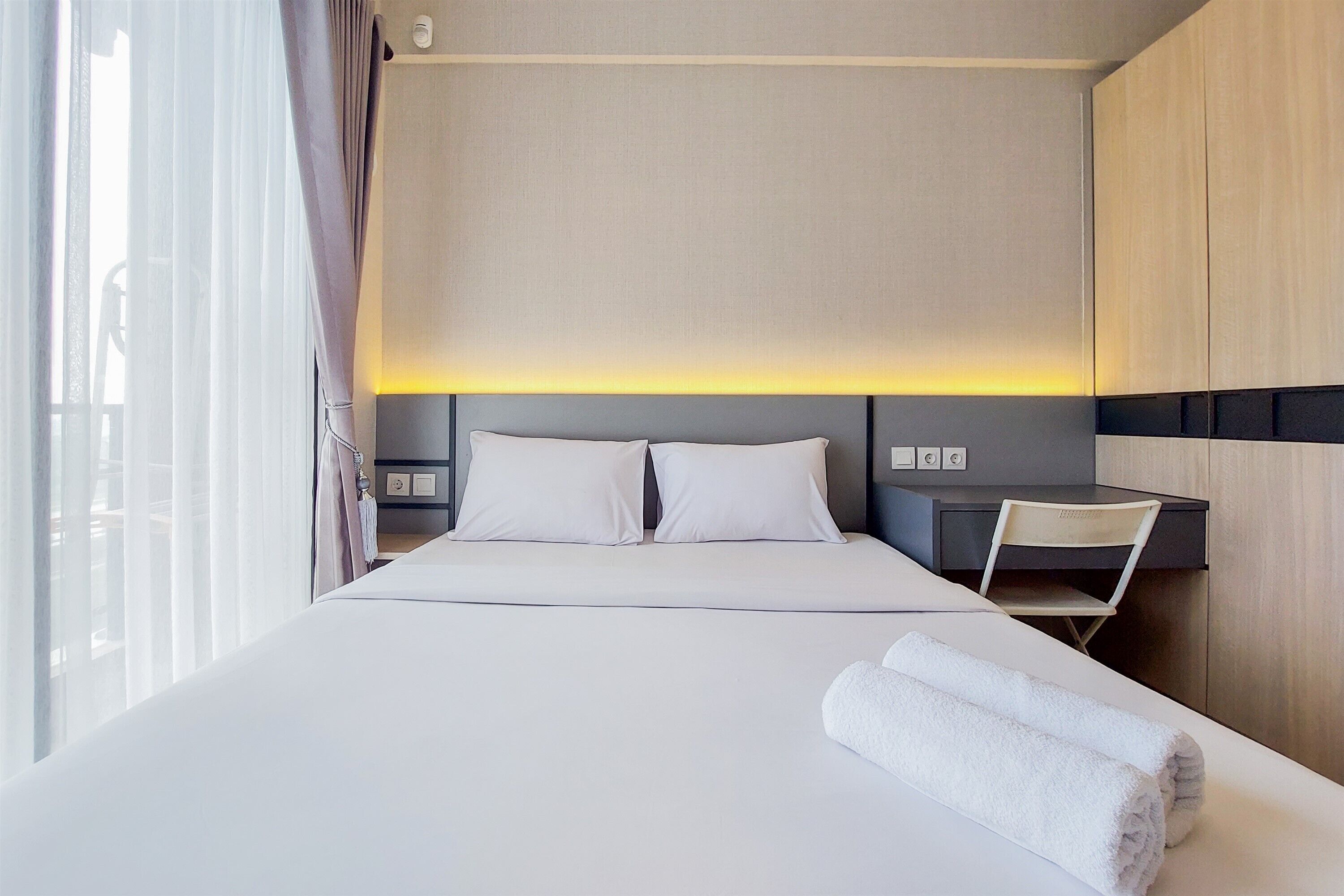 A hotel room with a bed, a desk, and a chair.