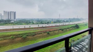 A view from a balcony overlooking a highway with multiple lanes, greenery, and distant buildings. - Gorgeous And Tidy Studio At Sky House Bsd Apartment (Pagedangan)
