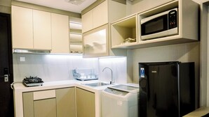 A modern kitchen with a built-in microwave, a black refrigerator, a dishwasher, and a gas stove. - Homey And Cozy Studio Room Daan Mogot City Apartment (Jakarta)