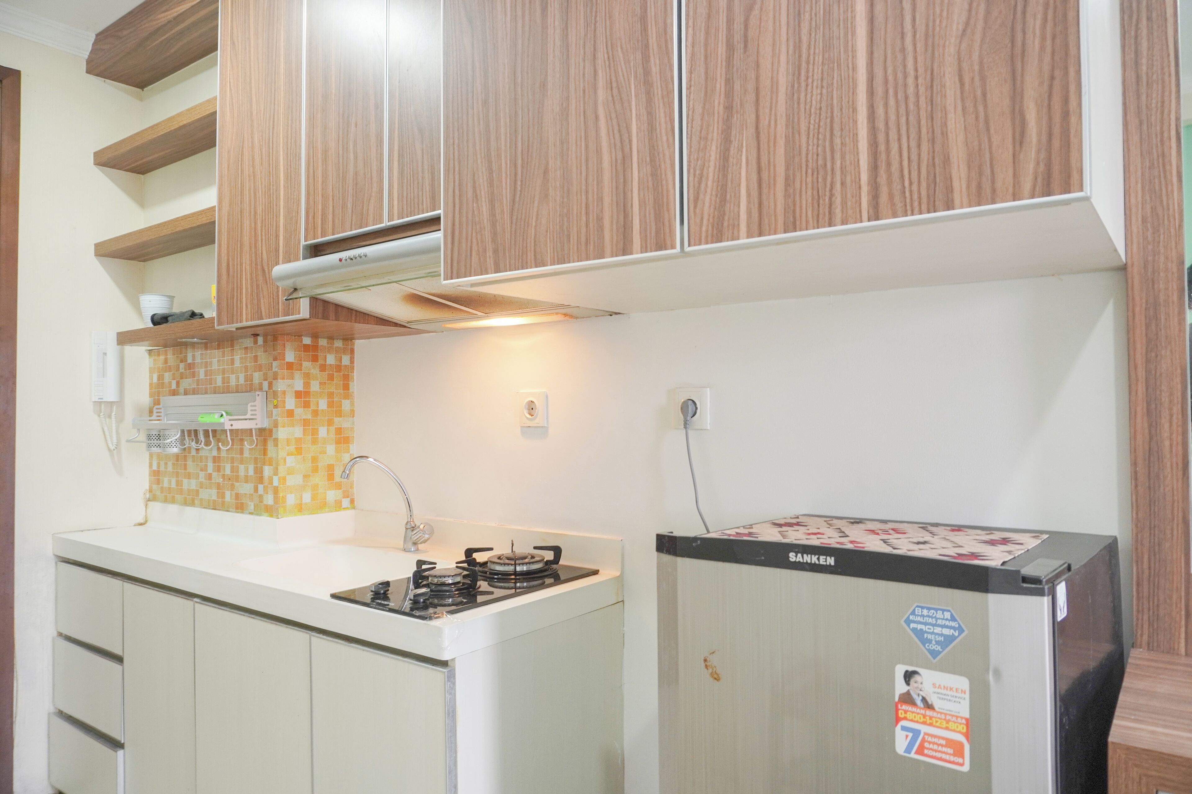 Cocina con armarios de madera, encimera blanca, lavabo y refrigerador.