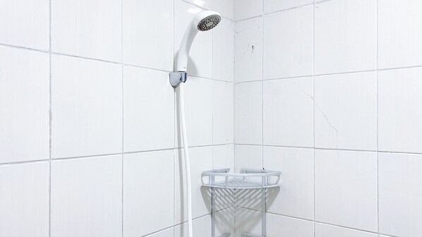 A white tiled shower area with a modern showerhead and a glass shower seat.
