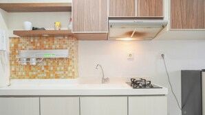 A kitchen with white cabinets, a tiled backsplash, a stainless steel sink, a gas stove, and a built-in oven. - Comfort Living And Homey Studio Signature Park Grande Apartment (Jakarta)
