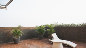 A rooftop patio with a lounge chair and potted plants. - Comfort And Homey 2Br Belmont Residence Puri Apartment (Jakarta)