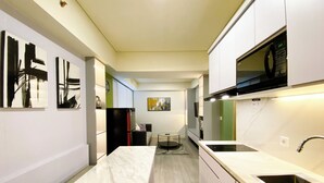 A modern kitchen with white cabinetry, a marble countertop, and a black microwave. - Best Homey 2Br At Meikarta Apartment (Cikarang)