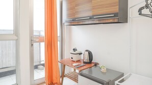 A compact kitchen with a microwave, kettle, and a small table. - Minimalist Studio Taman Semanan Indah Cengkareng Apartment (Jakarta)