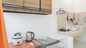 A compact kitchenette with a small refrigerator, a kettle, a rice cooker, and a coffee maker. - Minimalist Studio Taman Semanan Indah Cengkareng Apartment (Jakarta)