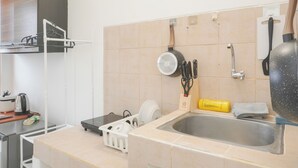 A kitchen with a sink, countertop, and various utensils. - Minimalist Studio Taman Semanan Indah Cengkareng Apartment (Jakarta)