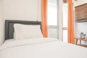 A neatly made bed with white linens, a grey headboard, and a small bedside table with a white kettle. - Minimalist Studio Taman Semanan Indah Cengkareng Apartment (Jakarta)