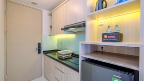 A compact kitchen with a black countertop, a built-in oven, and a water dispenser on the shelf. - Warm Studio At Tokyo Riverside Pik 2 Apartment (Teluknaga)