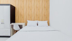 A bedroom with a wooden headboard, a white bed, and a white desk with a chair. - Gorgeous And Homey 2Br Serpong Garden Apartment (Cisauk)