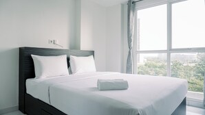 A modern hotel room with a large bed, white bedding, and a view of the city through a large window. - Wonderful 1Br Casa De Parco Apartment Near Ice Bsd (South Tangerang)
