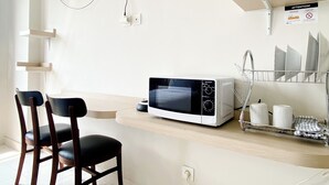 Une cuisine moderne équipée d’un four à micro-ondes, de chaises et d’un téléviseur fixé au mur.