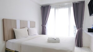 Ein Hotelzimmer mit einem großen Bett, weißer Bettwäsche, einem Holz-Kopfteil und Blick auf die Stadt durch das Fenster.