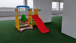 A children's play area with a slide and swings, set on artificial turf. - Cozy And Simply Studio Apartment At Urban Heights Residences (South Tangerang)