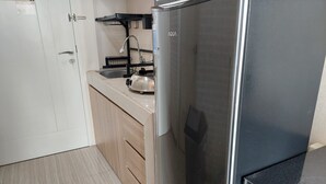 A kitchen with a stainless steel refrigerator, a sink, and wooden cabinets. - Cozy And Simply Studio Apartment At Urban Heights Residences (South Tangerang)