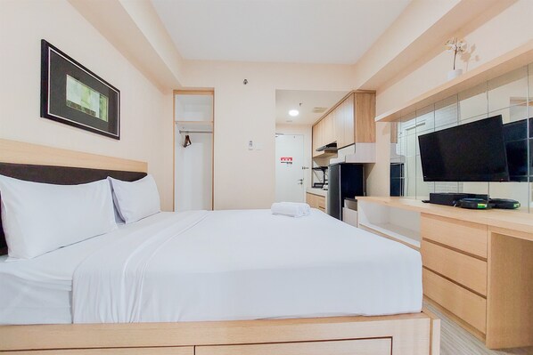A hotel room with a bed, a desk, a television, and a framed picture on the wall. - Cozy And Simply Studio Apartment At Urban Heights Residences (South Tangerang)