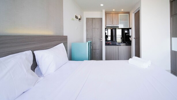 Una habitación de hotel con una cama, una kitchenette pequeña y una puerta que da a un baño.
