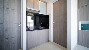 Cocina compacta con armarios de madera, encimera negra y campana extractora de acero inoxidable.