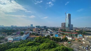 A cityscape with a mix of modern and traditional buildings, including a tall skyscraper under construction. - Good Deal 1Br Green Pramuka City Near Mall Apartment (Jakarta)