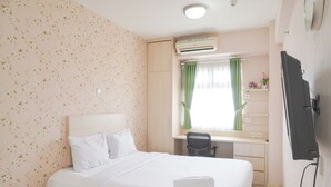 A hotel room with a bed, a desk, and a TV. - Good Deal 1Br Green Pramuka City Near Mall Apartment (Jakarta)