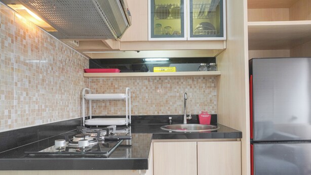 A compact kitchen with a gas stove, sink, and stainless steel refrigerator. - Good Deal 1Br Green Pramuka City Near Mall Apartment (Jakarta)