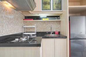 Une cuisine de taille réduite équipée d’une cuisinière à gaz, d’un évier et d’un réfrigérateur en acier inoxydable.