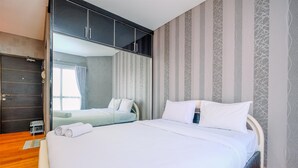 A hotel room with a large bed, a wardrobe, and a mirror. - Good Deal And Tidy Studio At Tamansari Semanggi Apartment (Jakarta)