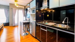 A modern kitchen with a stainless steel sink, black countertops, and wooden flooring. - Good Deal And Tidy Studio At Tamansari Semanggi Apartment (Jakarta)
