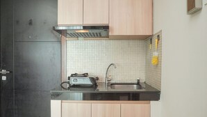 Una cocina con un refrigerador negro, un tostador, un fregadero y armarios de madera.