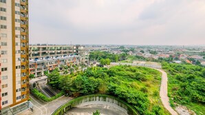 A high-rise building with multiple balconies and a curved road leading to a green area.