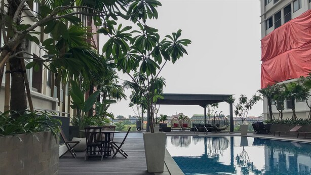 A poolside area with a wooden deck, lounge chairs, and a covered seating area.