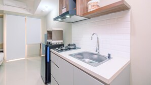 A modern kitchen with white tiles, a stainless steel sink, and wooden cabinets.