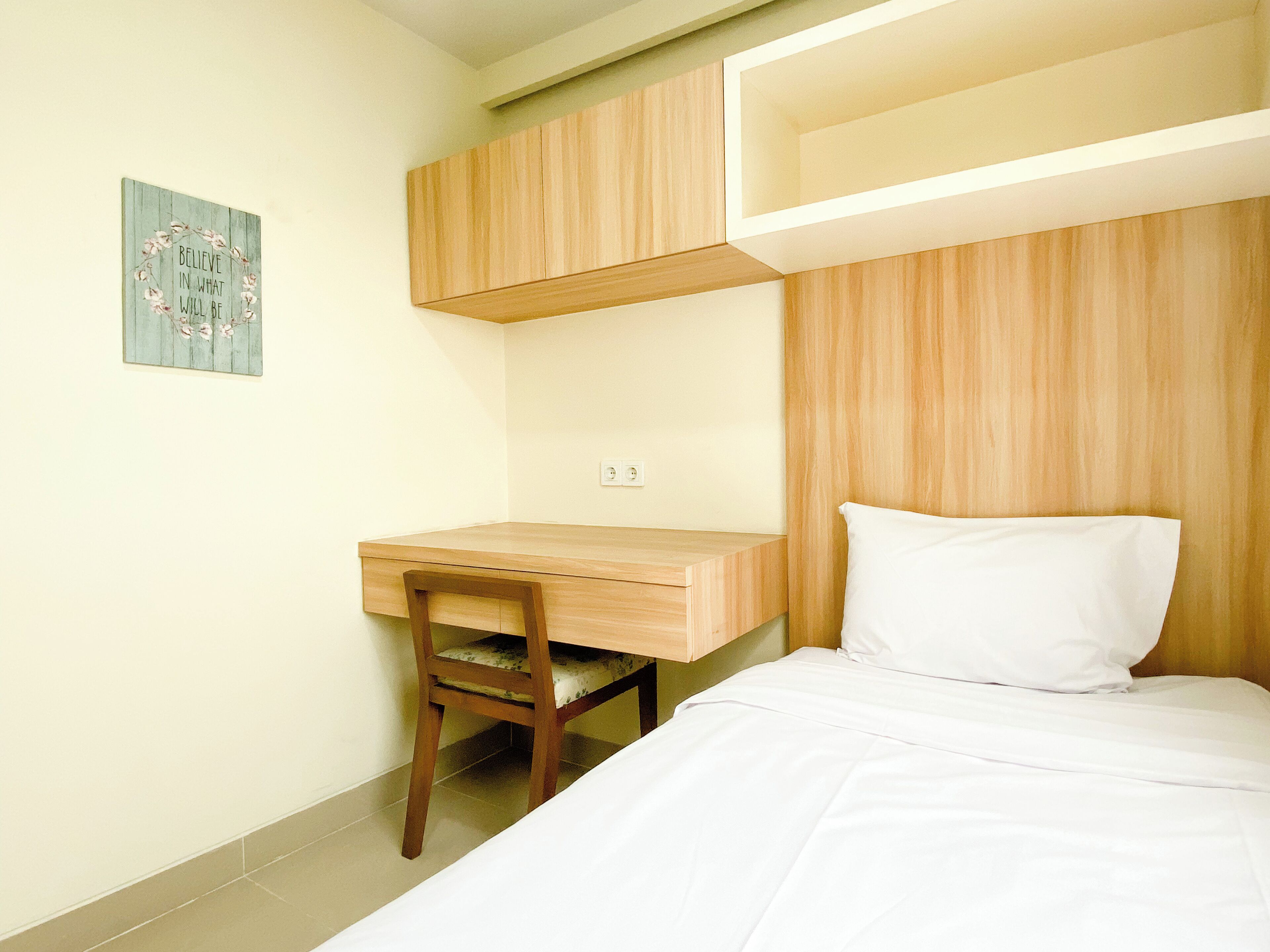 Een slaapkamer met een bed, een houten bureau en een stoel.