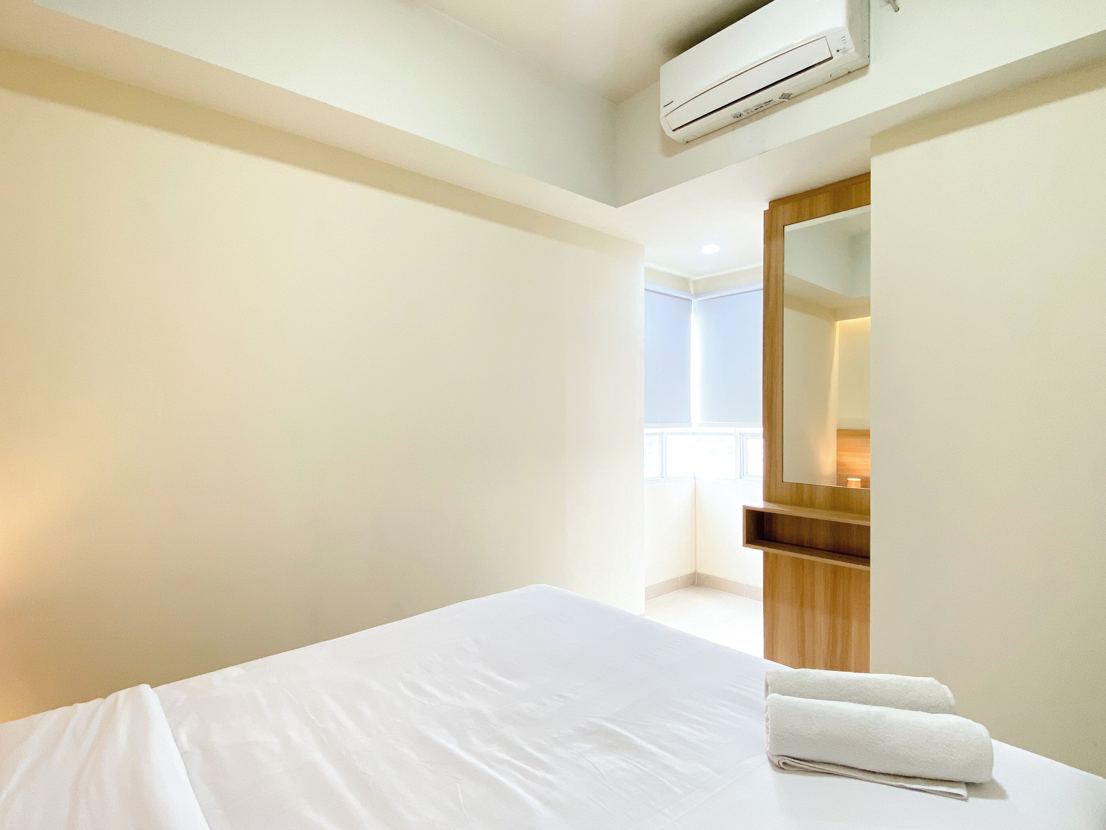 Habitación de hotel con una cama, un espejo y un equipo de aire acondicionado.