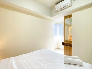 Quarto de hotel com cama, espelho e ar condicionado.