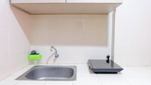 Un baño con un lavamanos, un dispensador de jabón verde y una balanza negra sobre el mostrador.