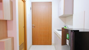Una cocina compacta con puerta de madera, un refrigerador y un lavabo.