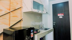 Cocina compacta con lavavajillas, microondas y protector de pared de madera.