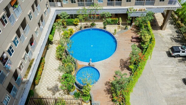 Vista aérea de un patio de hotel con una piscina central, rodeado de vegetación y un área de estar cubierta.